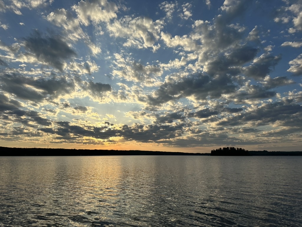 Cloud-filled sky over open water at Threemile Pond