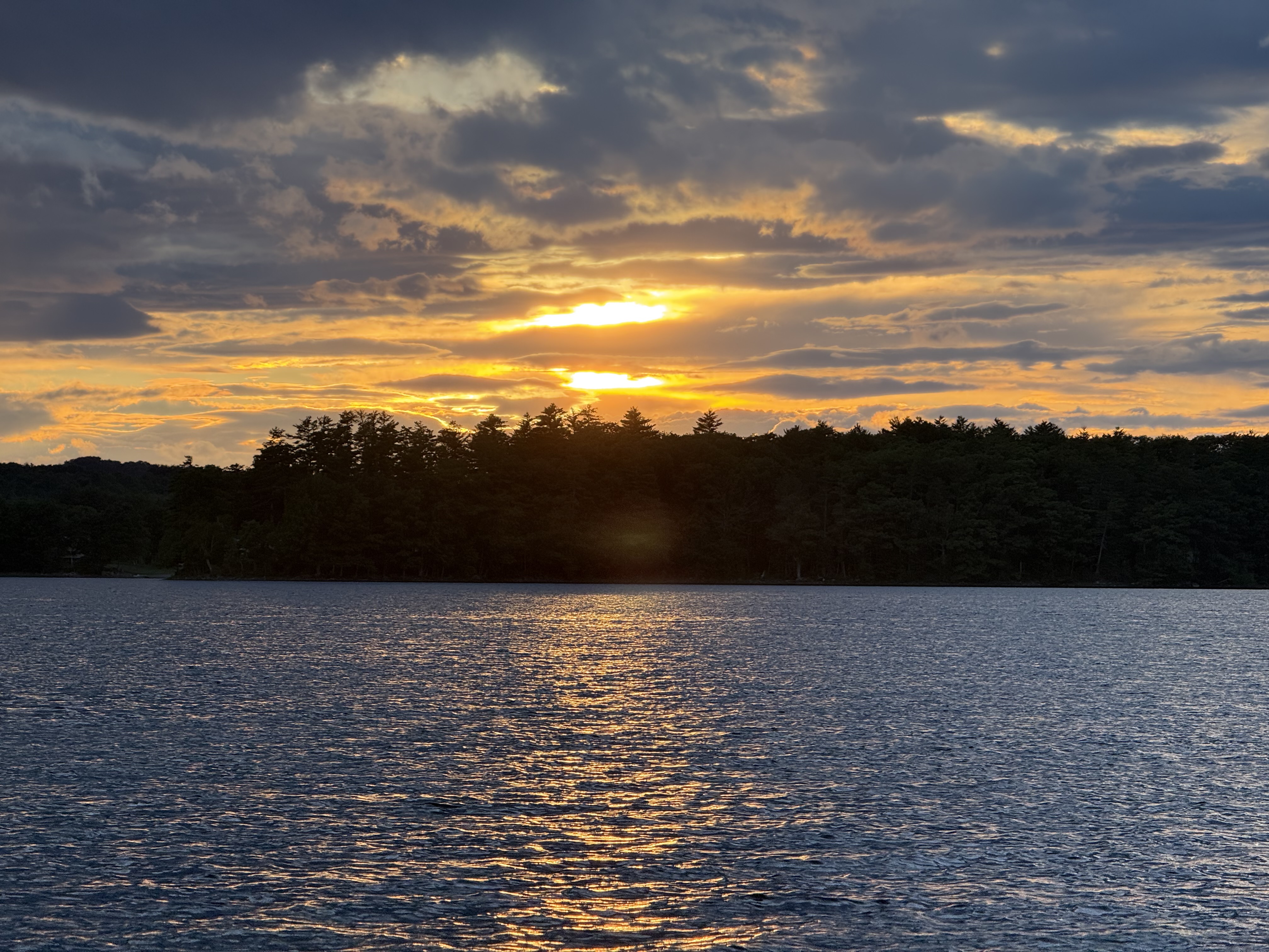 Dramatic sunset over Threemile Pond with golden light reflected on the water